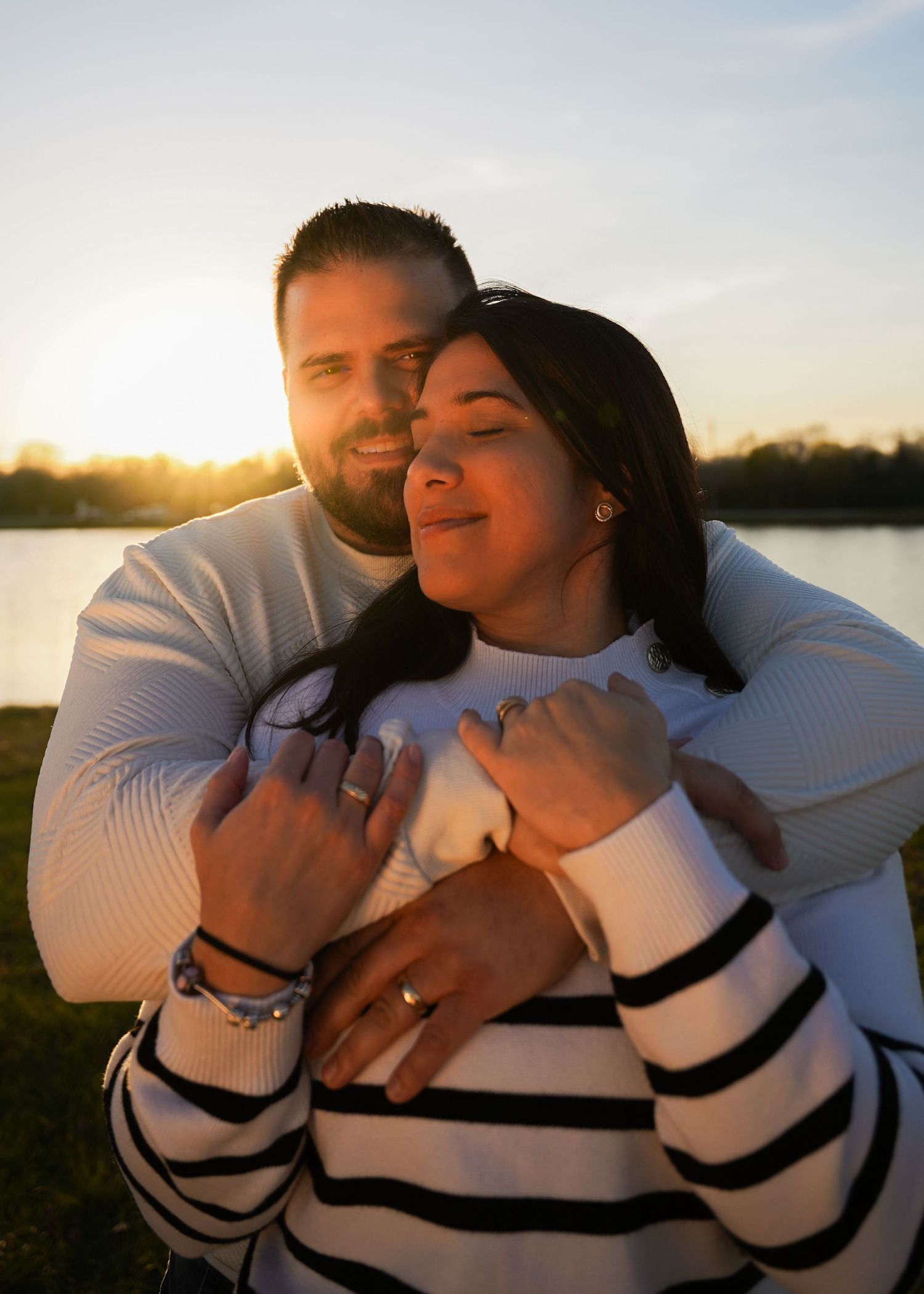 A couple sharing an intimate embrace at sunset by a lake.