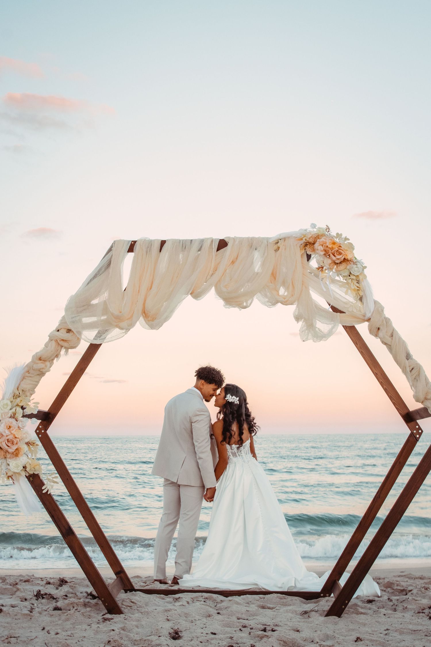 Coastal wedding photography with bride and groom underneath of an arch in Fort Pierce at sunset in November