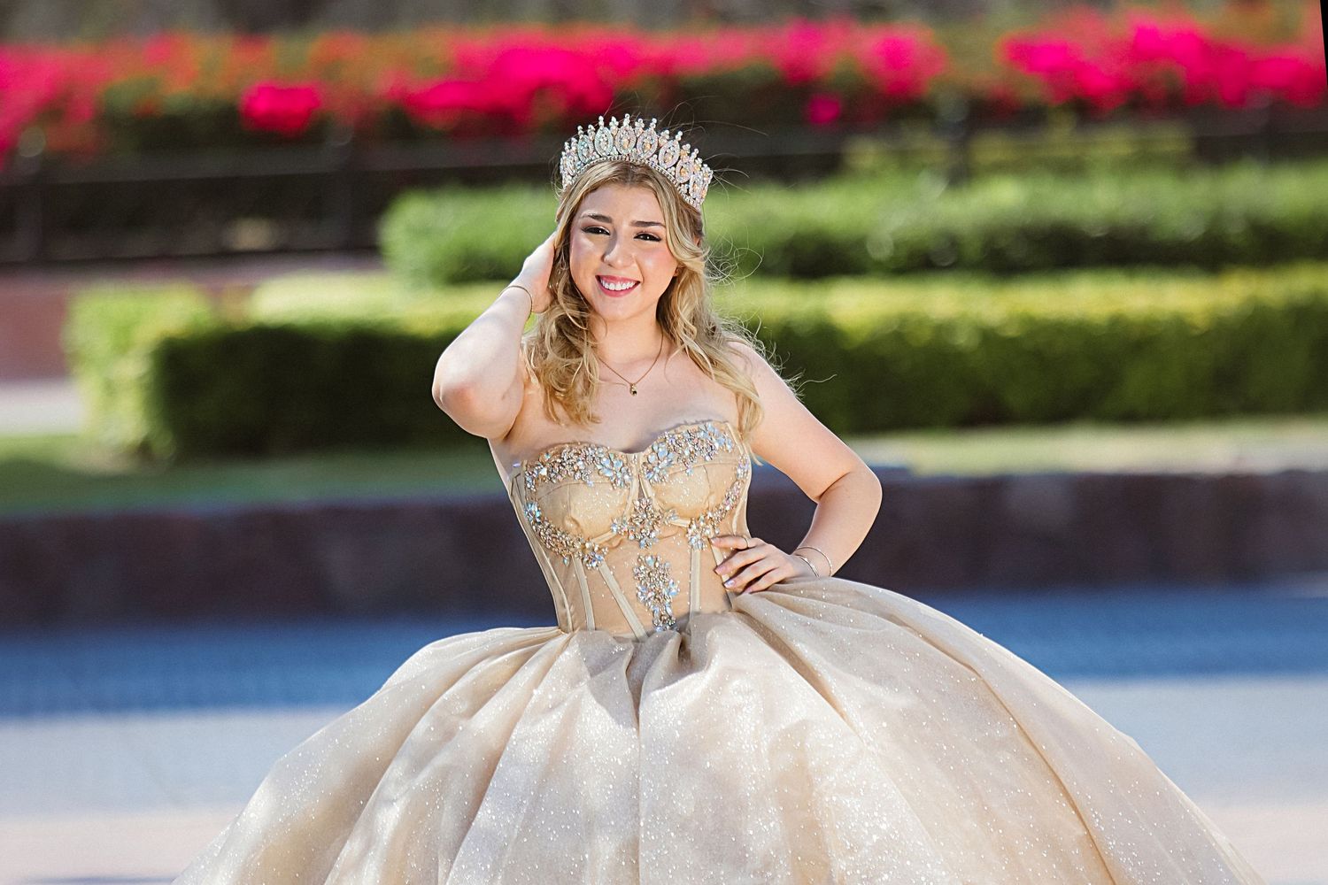 Ornate silver ballgown with crystal embellishments photographed in formal garden setting.
