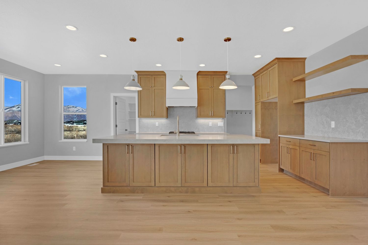 Spacious new construction kitchen with light maple cabinets, large island, pendant lights, and mountain window views.