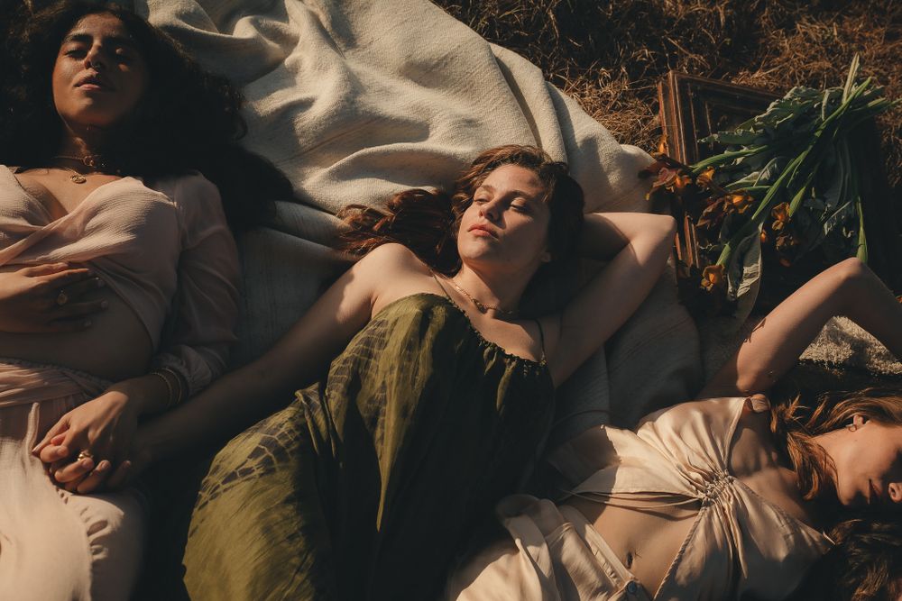 Dreamy sunlit scene of people relaxing outdoors on white fabric.