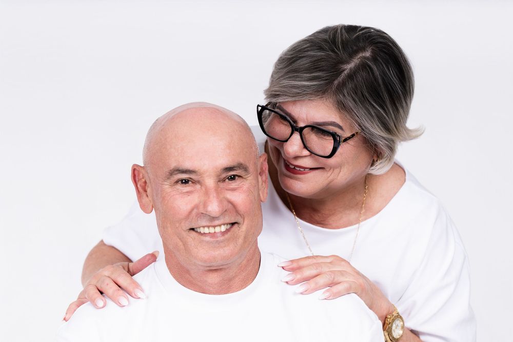 Intimate portrait of a senior couple in white attire sharing a tender moment.