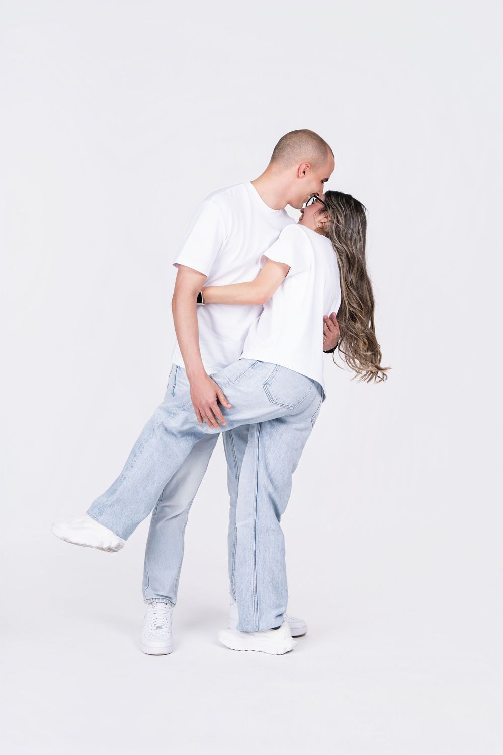 Romantic couple in matching outfits sharing an intimate dance pose against white background.