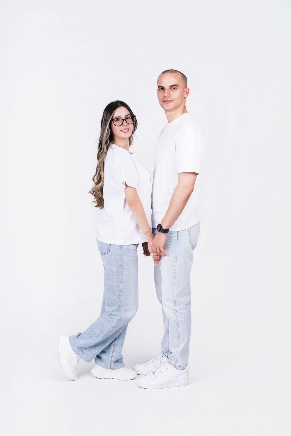 Contemporary couple in coordinated white and denim outfits posing together.
