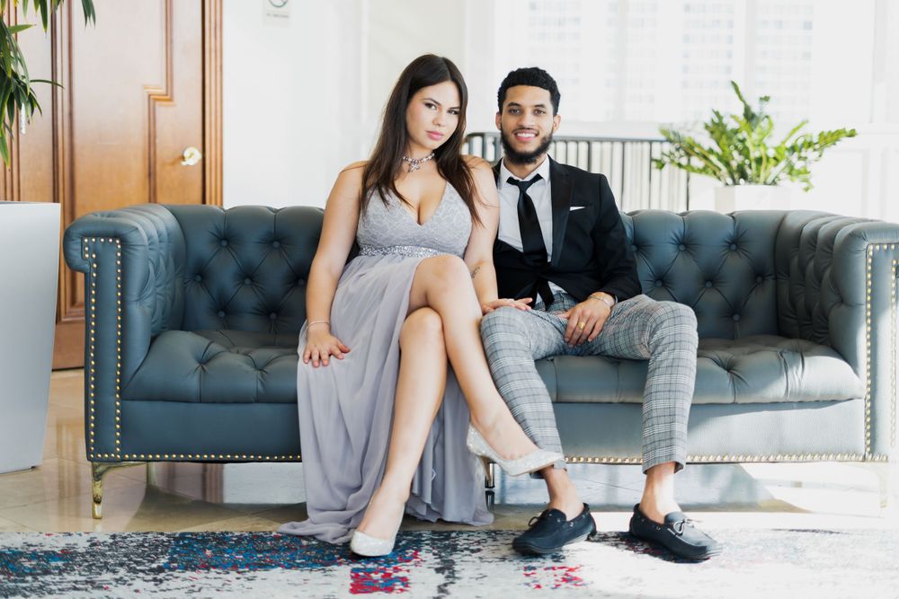 Stylish couple relaxing on gray tufted couch during photo session.