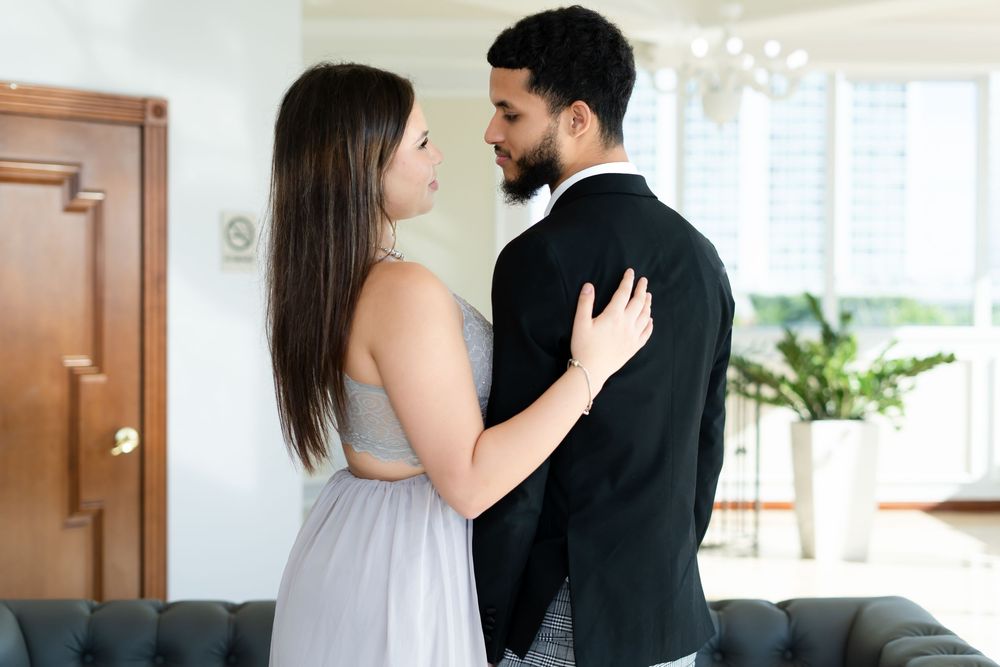 Couple in black and white outfits embracing in romantic poses against a bright interior.
