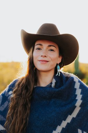 Southwestern fashion portrait featuring turquoise jewelry and a blue poncho at sunset.