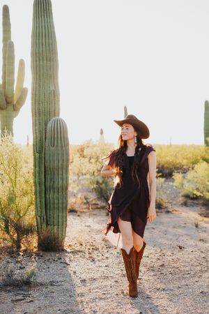 Cowgirl outfit photoshoot in desert with tall saguaro cactus at golden hour.