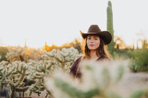 A western fashion portrait framed by desert flora and saguaro cactus during golden hour.