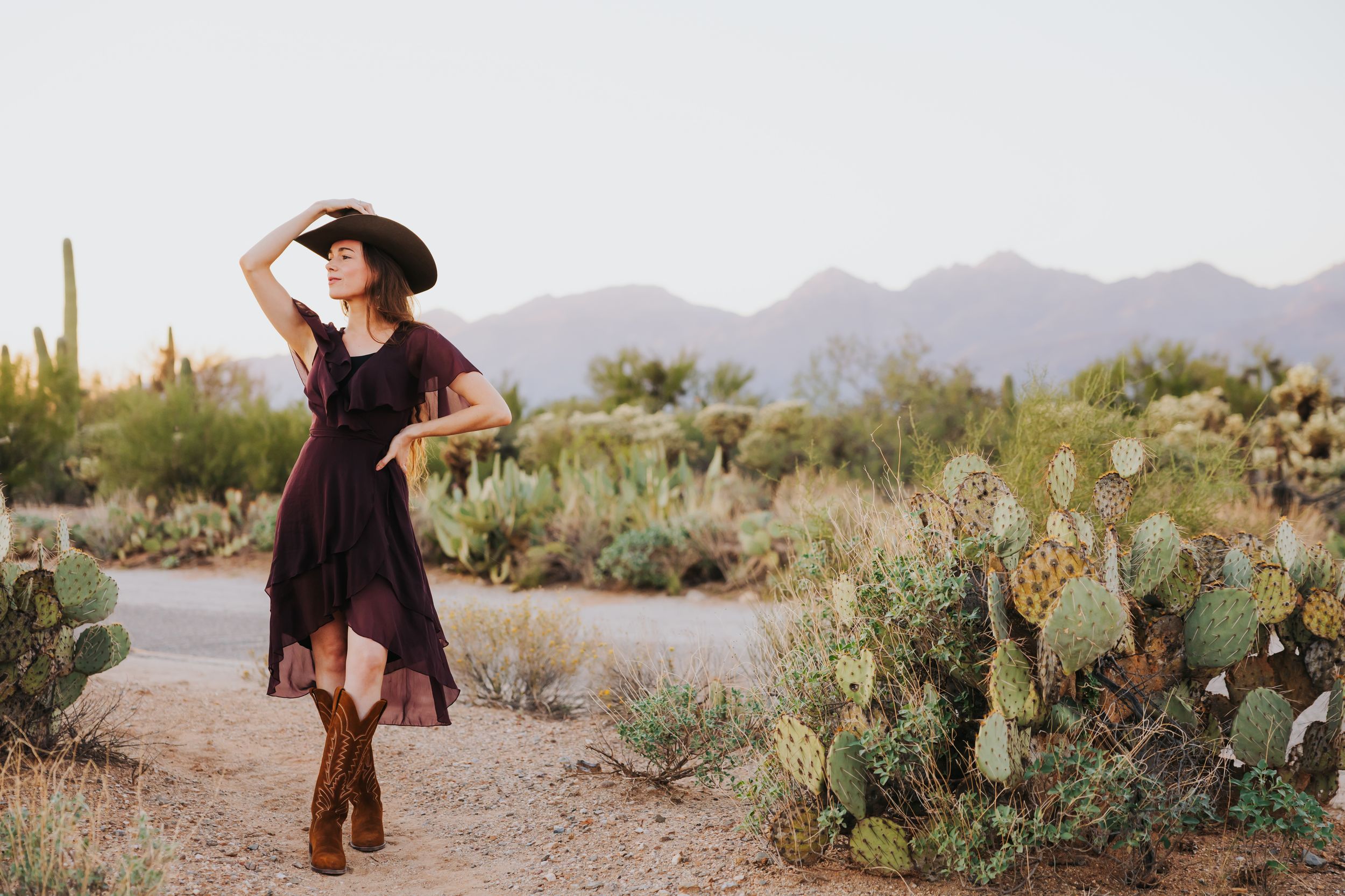 A western fashion shoot in a desert landscape with mountains and various cacti species.