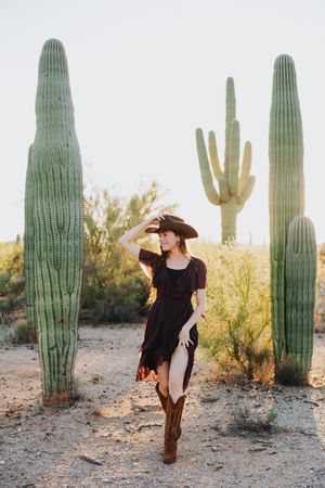 A western-styled photo shoot in a desert landscape with tall saguaro cacti at sunset.