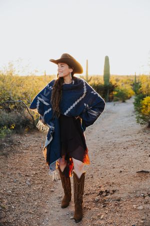 Southwestern style photography with a blue patterned poncho and brown boots in desert terrain.