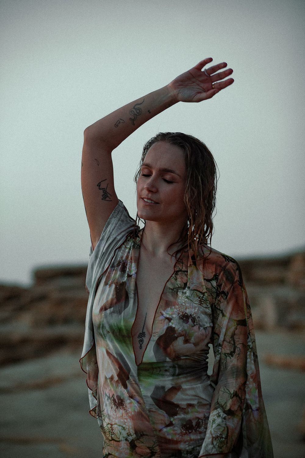 Artistic portrait with wet hair and floral dress against neutral background.