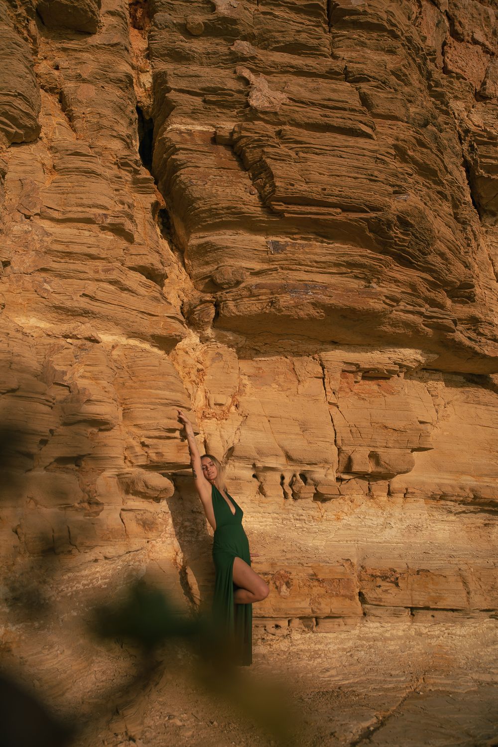 Figure in dark dress silhouetted against towering sandstone cliff face.