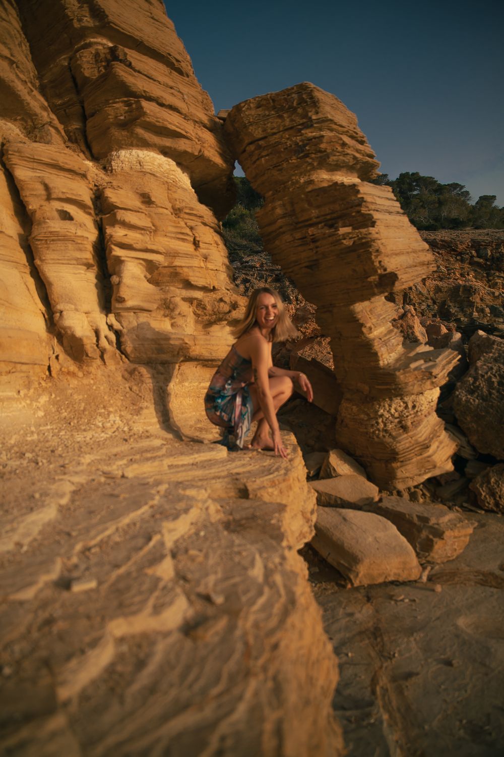 Person climbing on orange sandstone rock formations during golden hour.