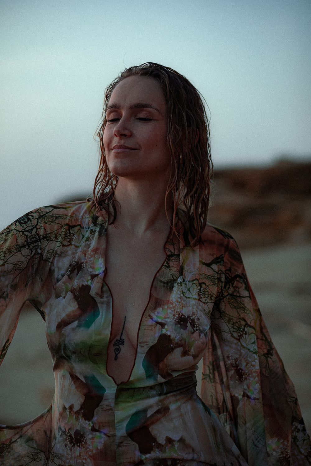 Atmospheric portrait with floral dress against moody sky background.