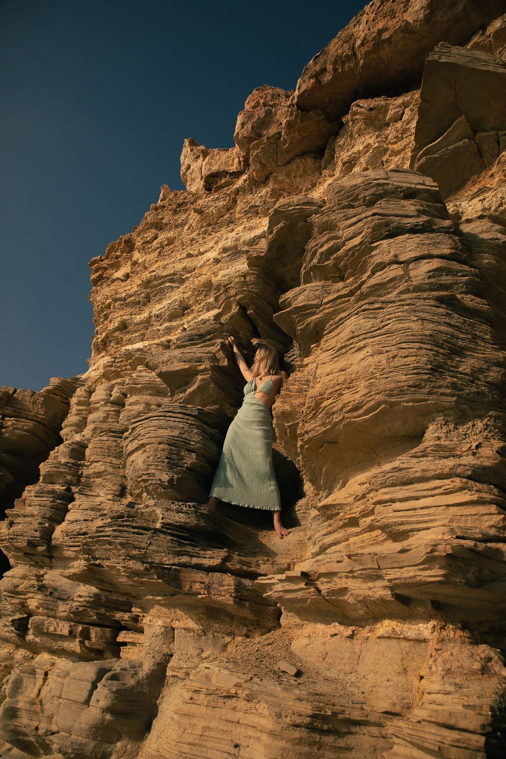 Figure exploring dramatic sandstone cliff formations in desert landscape.