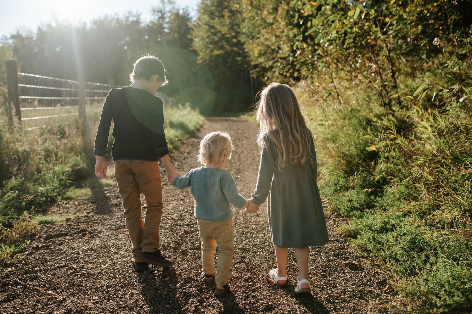 A family shares an intimate moment together in a scenic meadow with mountains and trees in the background.