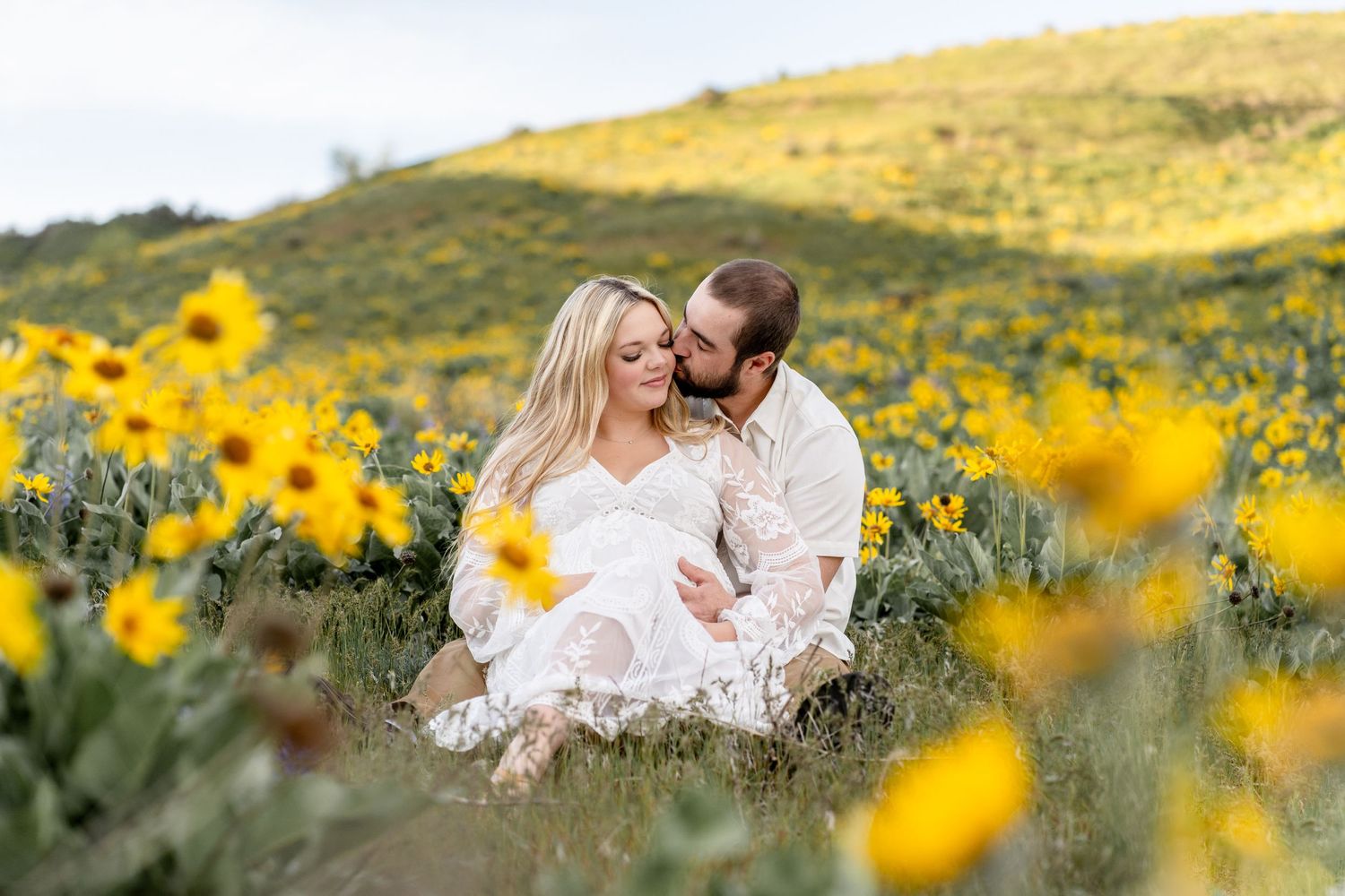 A romantic moment in a sunflower field at sunset with gentle mountains in the background.
