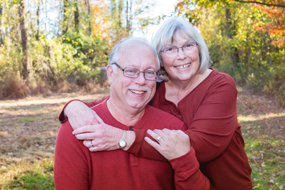 Happy senior couple smiling together outdoors in a colorful autumn setting wearing red.