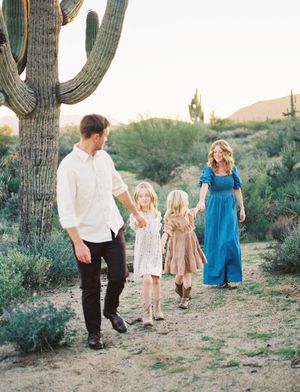 Family walking together through a desert landscape with tall saguaro cacti at sunset.
