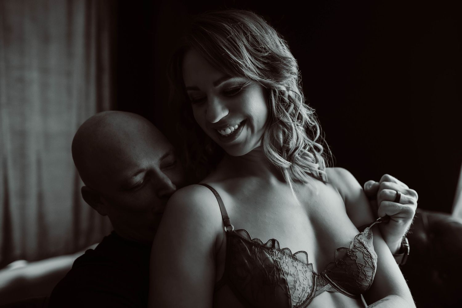 Intimate portrait of a couple sharing a tender moment in elegant formal attire during a boudoir photoshoot.