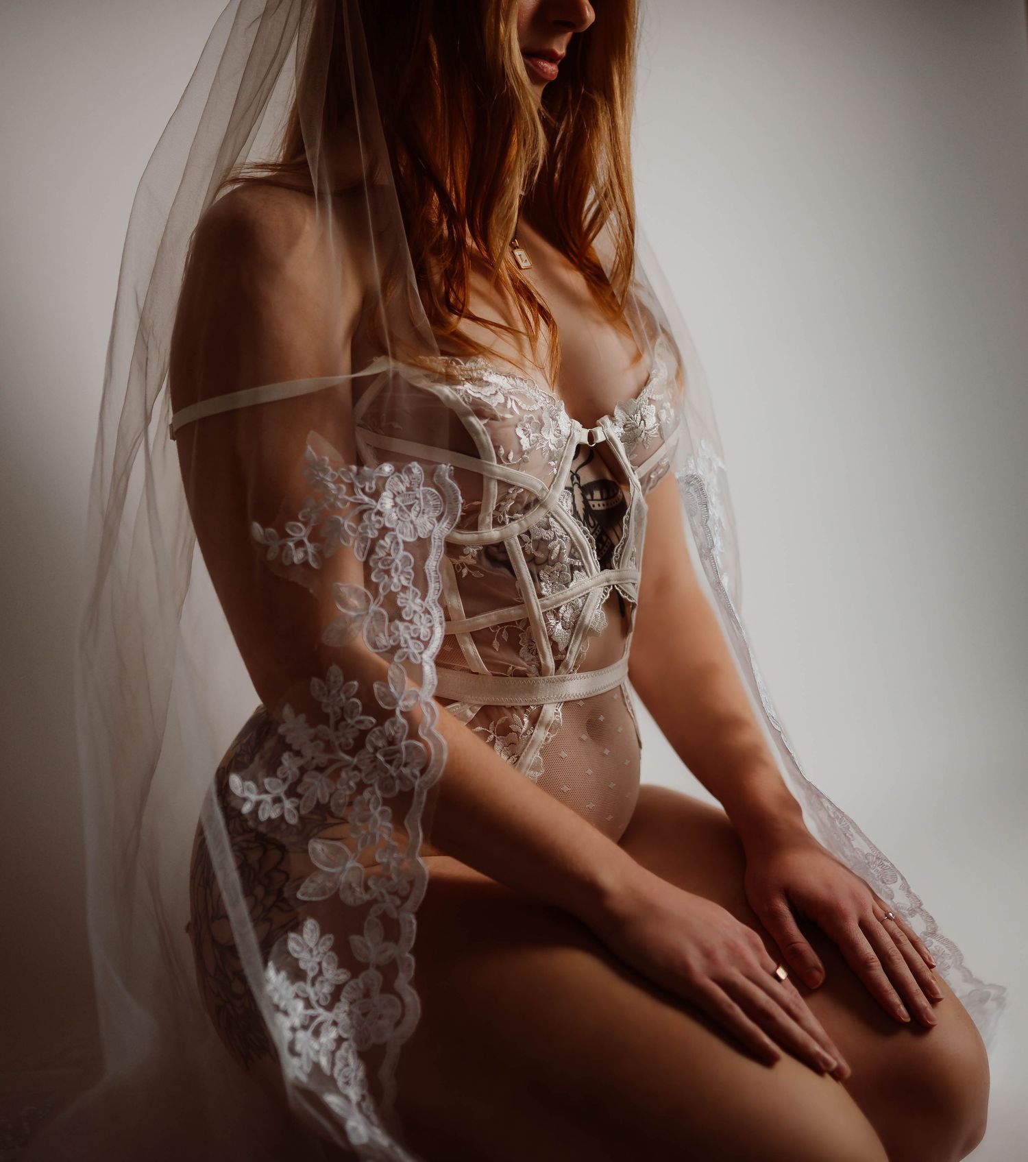 Bride wearing white lace corset lingerie and veil in an artistic boudoir photography session with Boudoir by KJ in Hudson, Wisconsin.