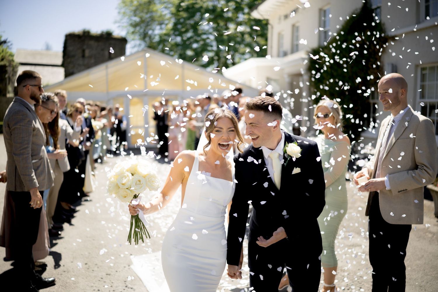 Bride and groom holding hands and laughing during confetti walk