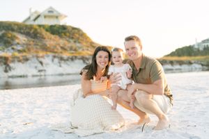 Family portrait on sandy beach with coastal cliffs in background.