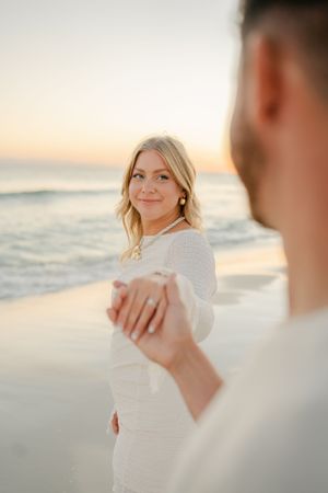 Intimate beach moment between couple holding hands at golden hour.