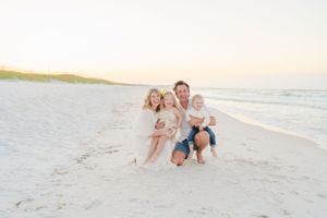 Family portrait on pristine white sand beach during golden hour.