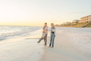 People walking along a pristine white sandy beach at sunset with soft golden light illuminating the shoreline.