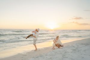 Playful beach scene with people jumping and running at sunset.