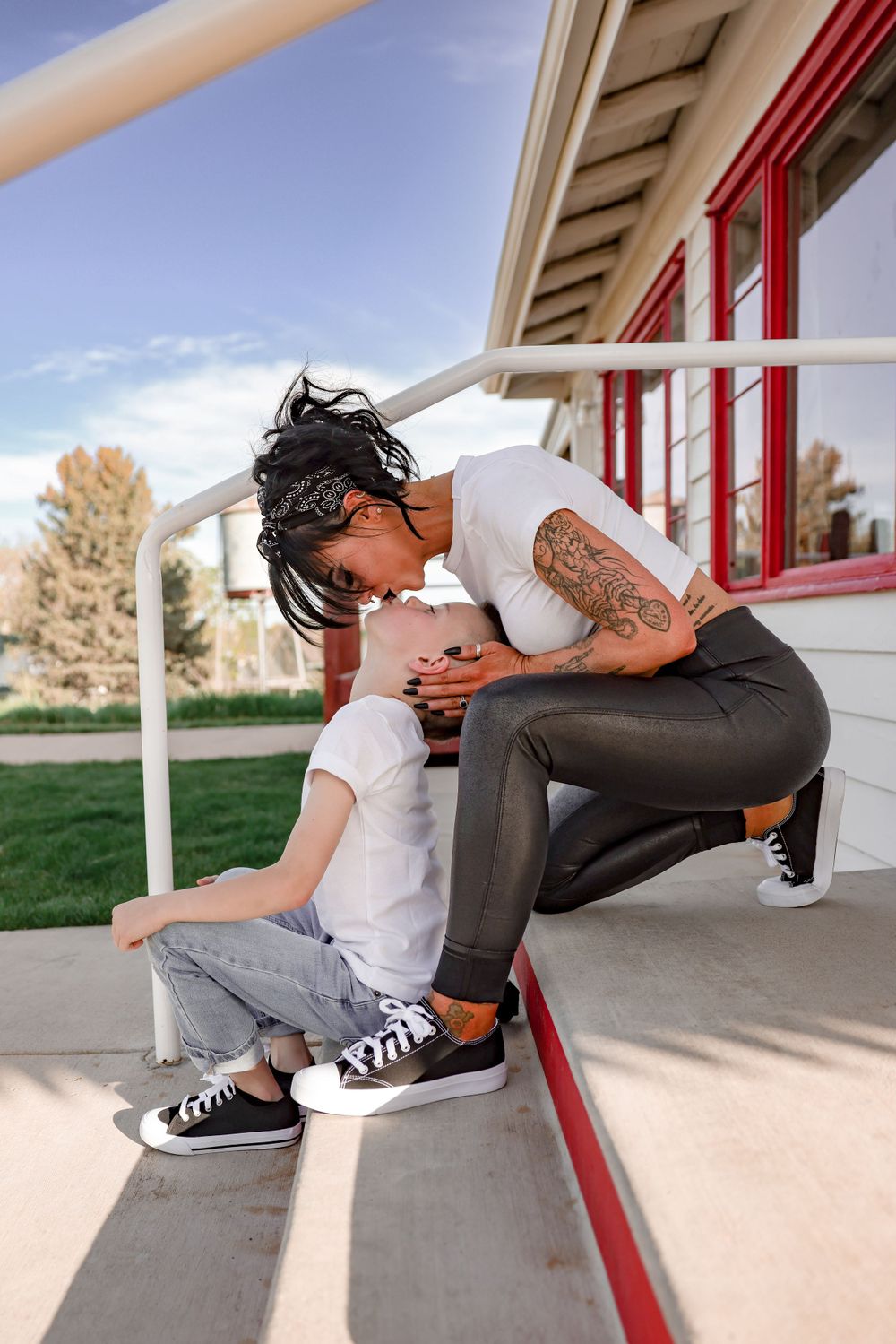 Playful moment shared on concrete steps with a white and red building in the background.