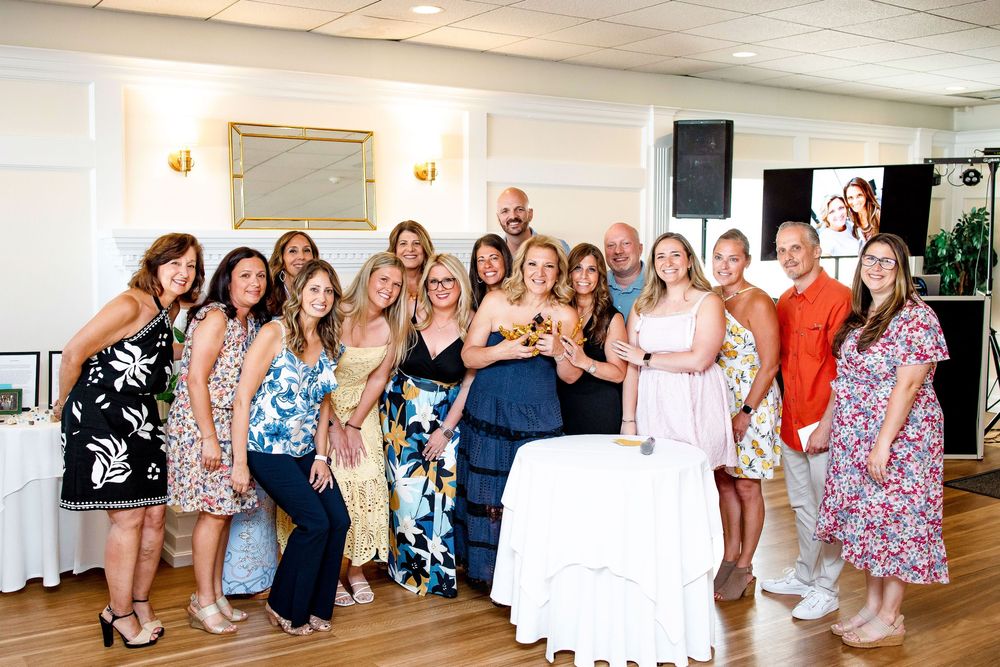 A panoramic shot shows a group of wedding guests posing together in a row inside an elegant reception venue.