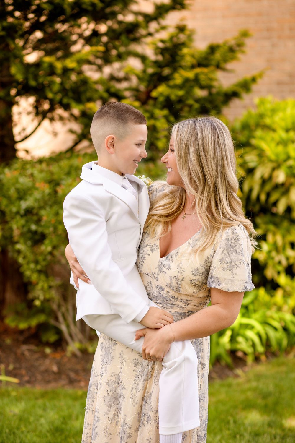 A tender moment captured in a garden setting with white clothing and floral patterns.