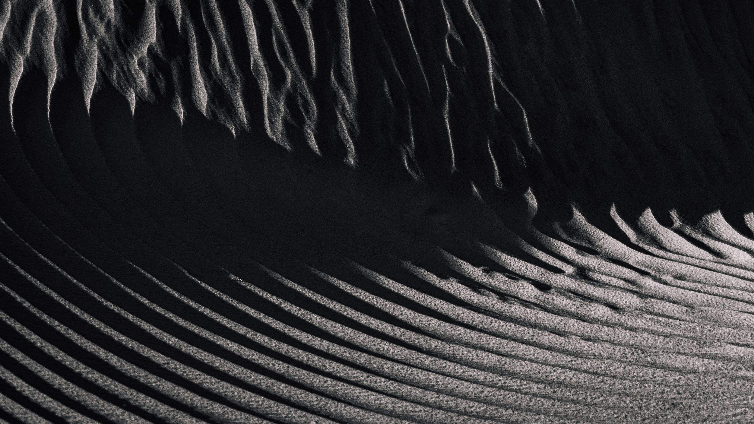 Sand dunes transition from falling to organized pattern of sand.