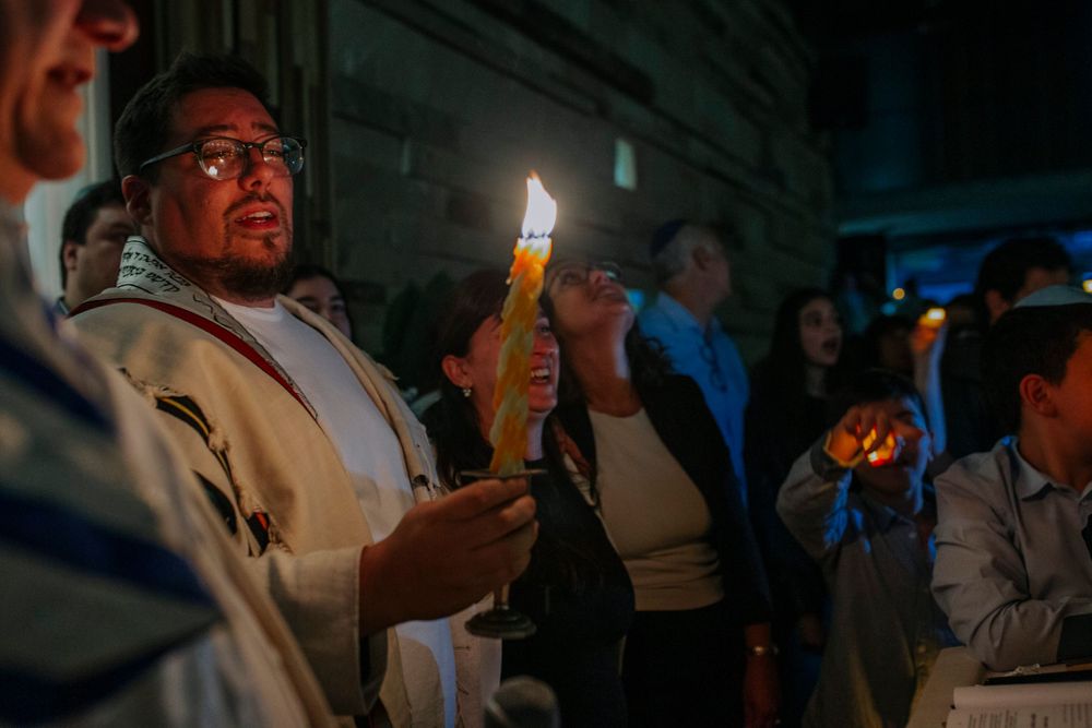 Person holding a lit candle during an evening vigil ceremony.