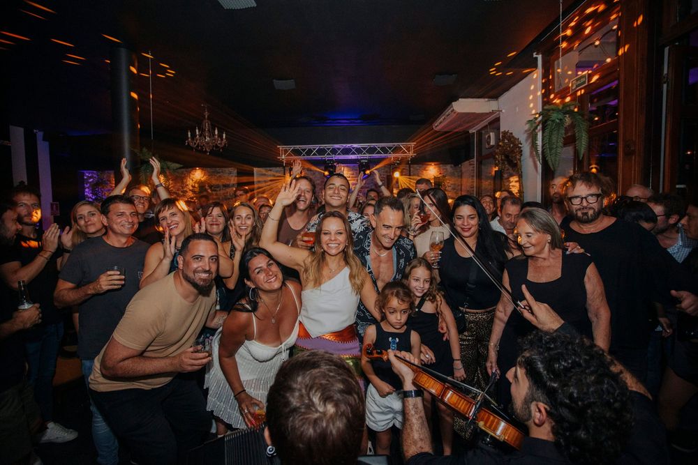 Large group of smiling people posing together at a lively nighttime outdoor party event.