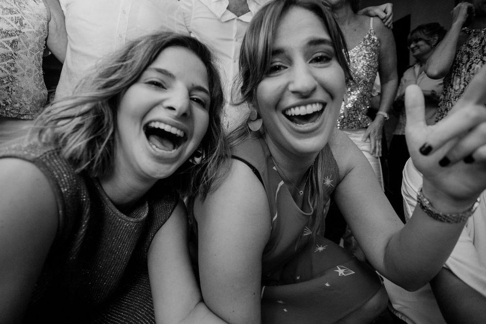 Two friends laughing together in a black and white selfie photo.