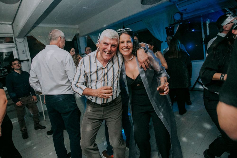 People dancing and celebrating together at an indoor party with blue lighting.