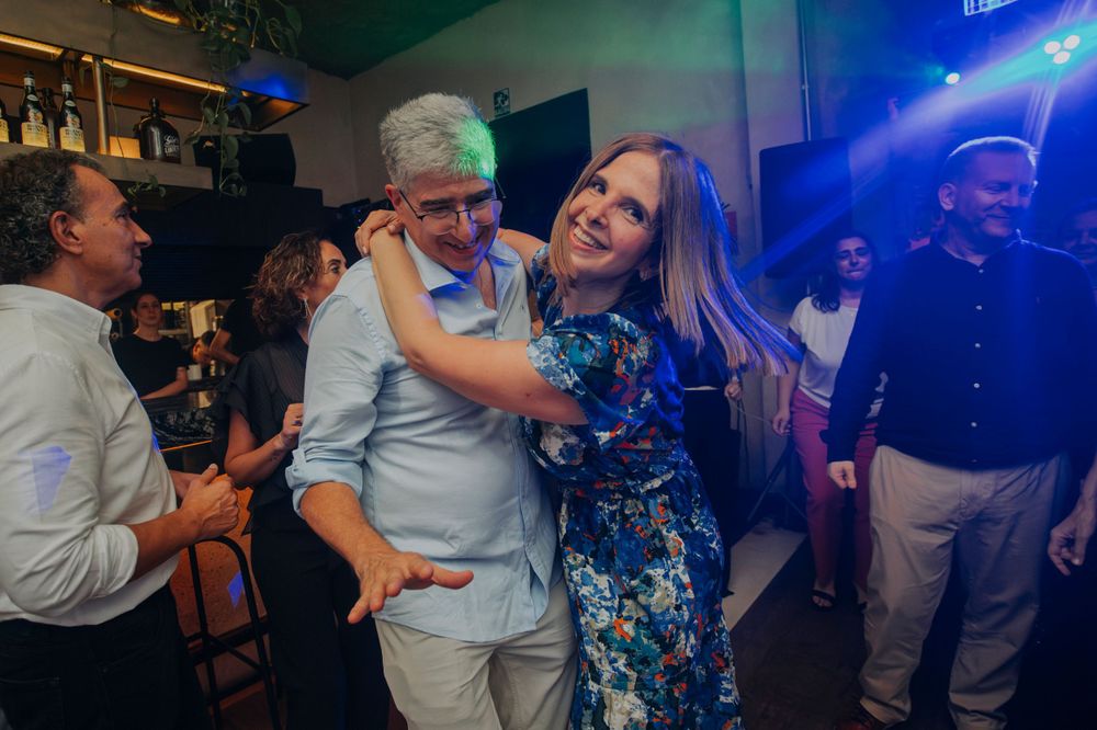 People dancing and embracing at a party with blue ambient lighting.