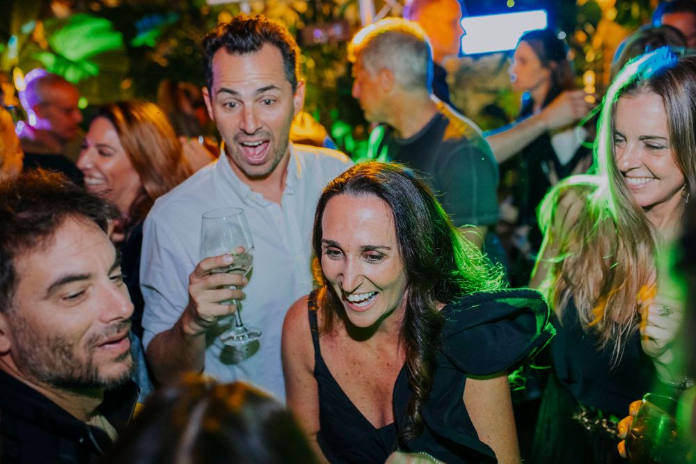 Energetic party crowd enjoying drinks under colorful lighting at a nightclub.