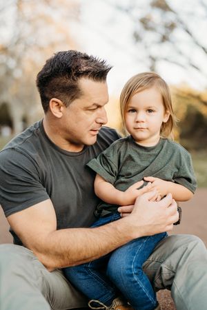 A parent and child share a tender moment together outdoors during an autumn photo session.