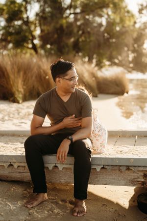 Person relaxing on wooden boardwalk during sunset with warm lighting.