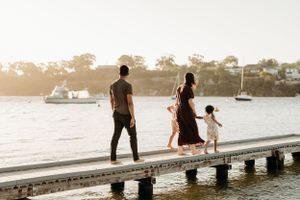 Silhouettes of people relaxing on a waterfront dock at sunset.