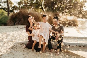 Family photoshoot at riverside dappled sunlight through trees.