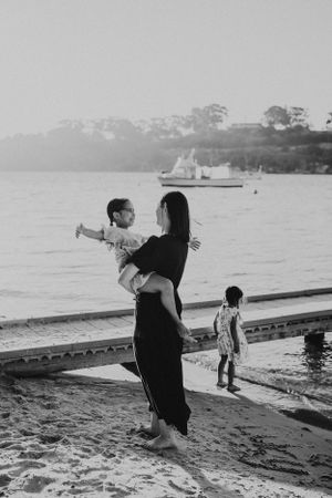 A family enjoying sunset moments on a wooden dock by the water in black and white.