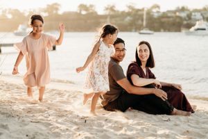 Family enjoying playful moments together on sunlit beach.