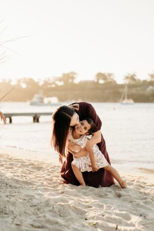 Couple lounging intimately together on sandy beach during golden hour.